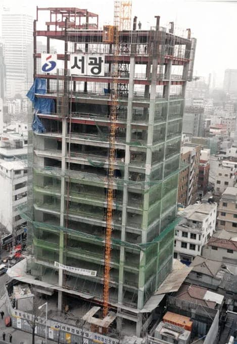 안전망이 설치된 고층 건물 골조와 주변 도심 전경